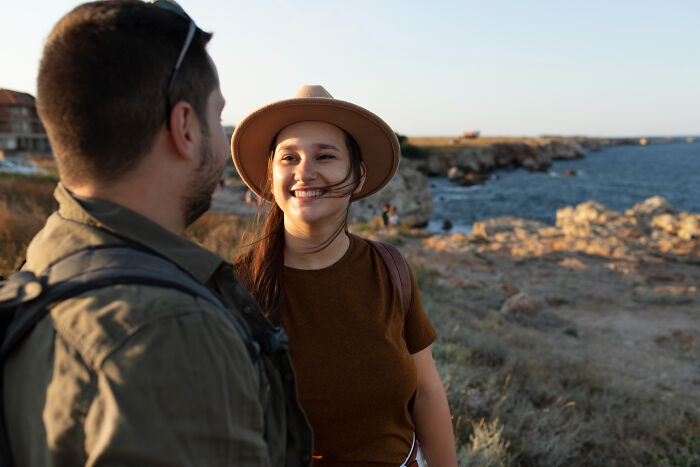 Man romantically interacting with a woman outdoors near rocky coastline, highlighting toxic relationship behavior concerns.