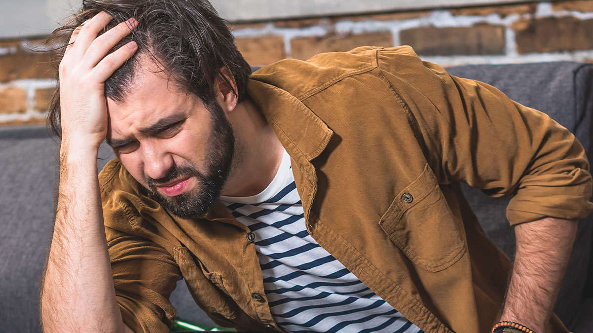 Man sitting indoors looking stressed and frustrated, illustrating husband with a real problem in a nursery setting.