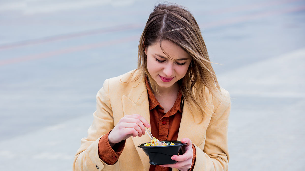 Woman eating her own food in a bowl outside, illustrating a friendu2019s diet at a wedding and related drama