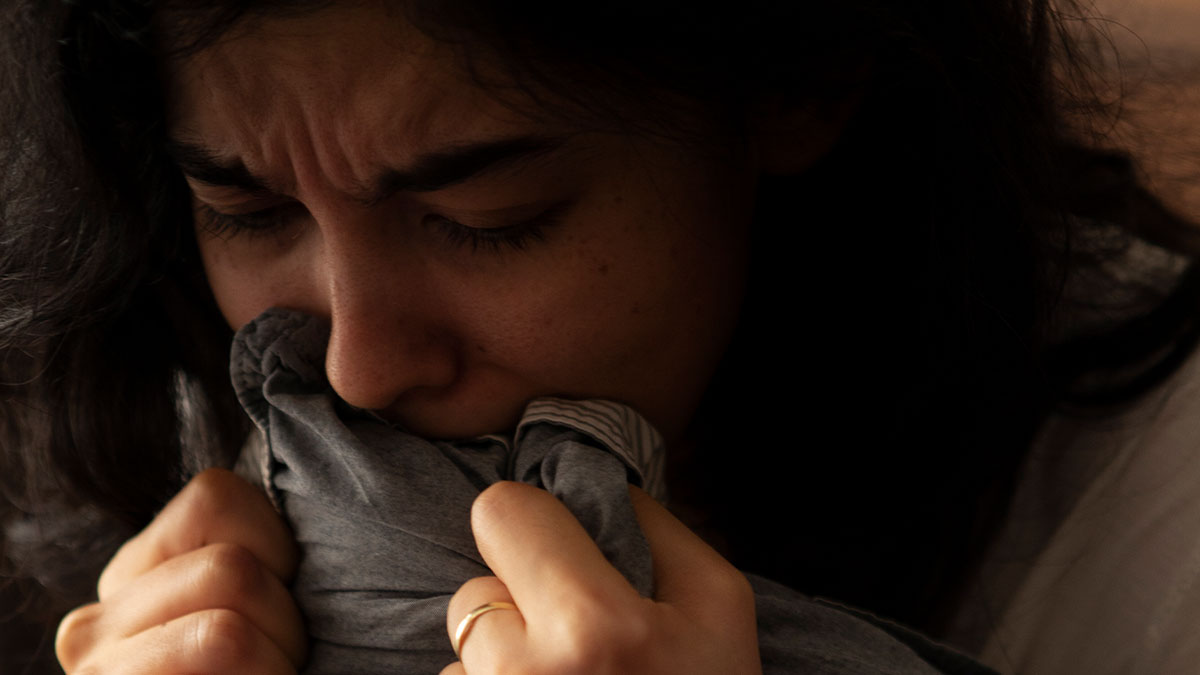 Woman looking devastated and emotional, holding fabric close, reflecting feelings of being out of her model boyfriend's league