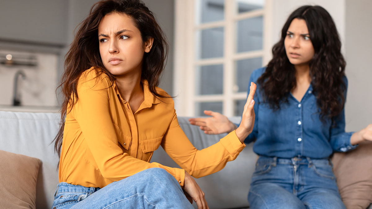 Two women having a tense argument on a couch, illustrating a friendship ending over a purse fiasco.