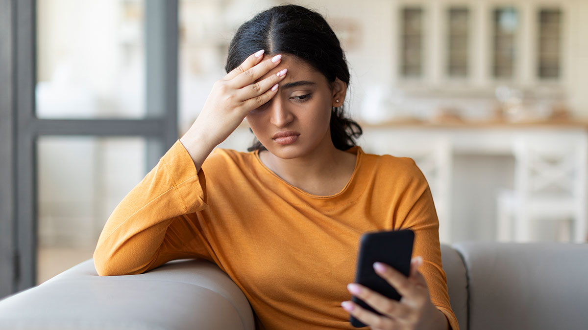 Woman looks upset holding phone, reflecting on being backup and second choice in her relationship.