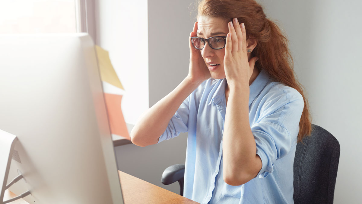 Woman in glasses at work looking shocked while setting up WIC profile discovering husbandu2019s affair baby news