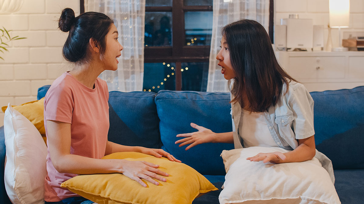 Two women having a tense conversation on a couch, reflecting conflict involving a woman forbidding her BIL from talking to her.