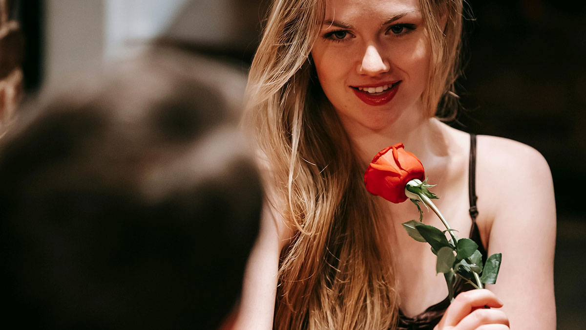 Woman on a date holding a red rose, reflecting on motherhood and artificial insemination plans.