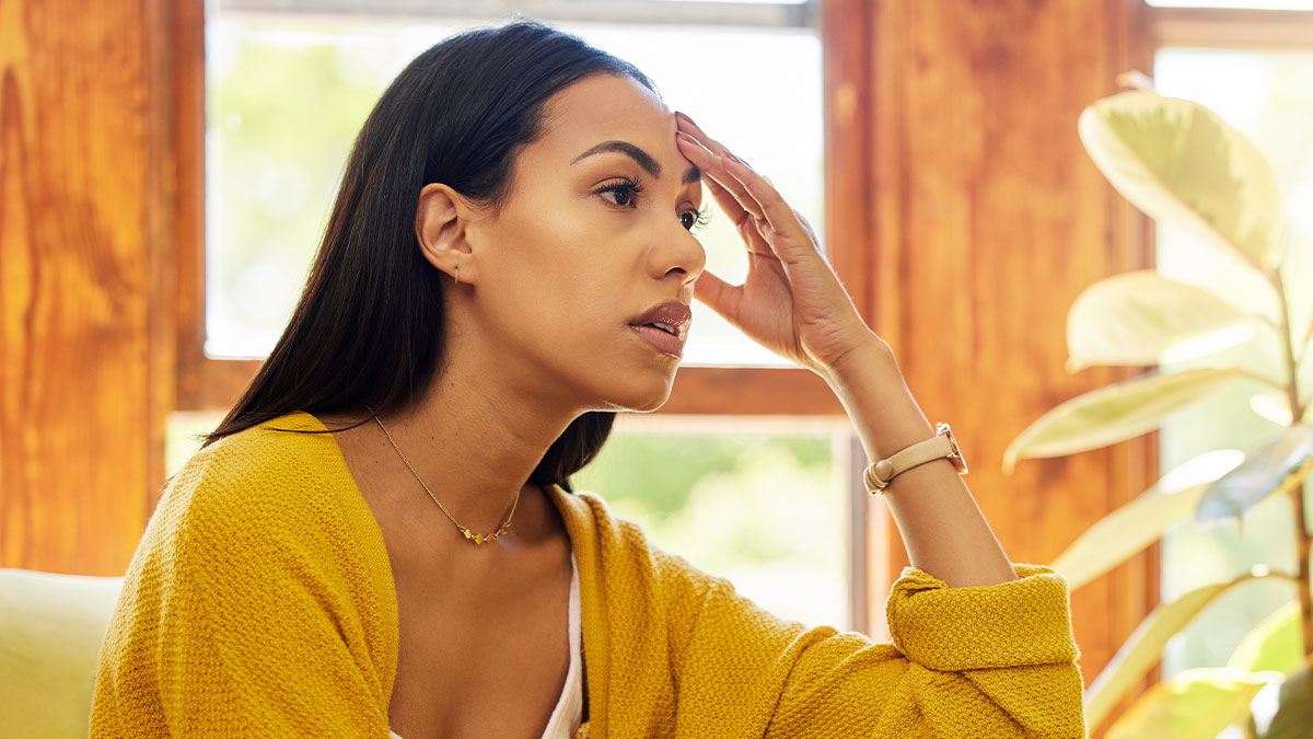 Woman in yellow sweater looking stressed indoors, illustrating woman rents out husbandu2019s man cave after he refuses to help.