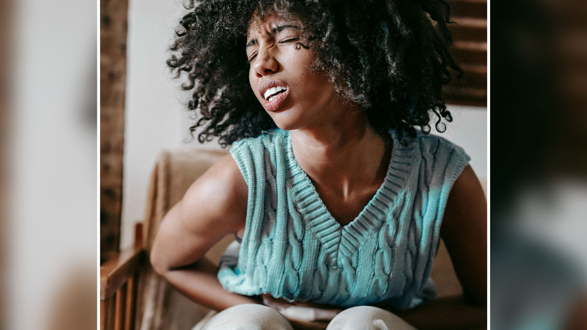 Young woman grimacing in pain while holding her stomach, illustrating discomfort after eating a poisoned cake scenario.