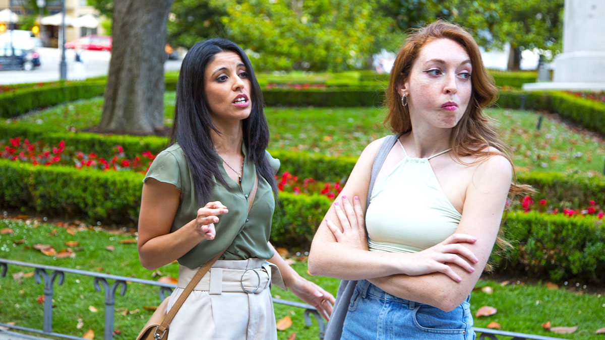 Two women in a park having a tense conversation about a friend who wonu2019t pay her back.