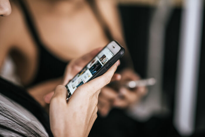 Person holding a smartphone browsing products online, illustrating overhyped products people say to stop buying.