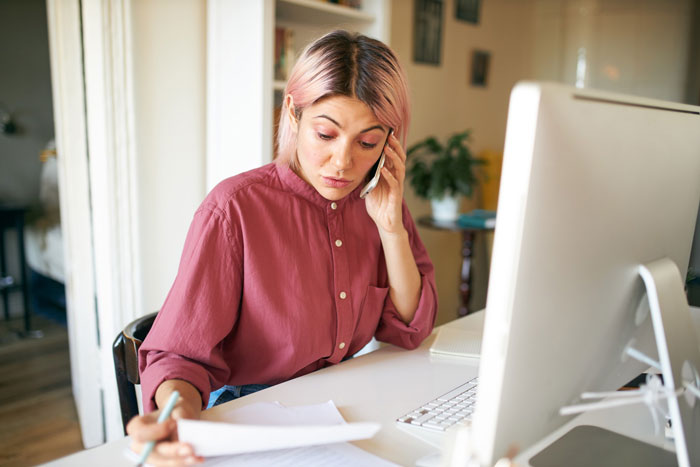 Woman working at desk on phone, focused and concerned as her Tenerife vacay is blocked by her boss’s decision. Woman working at desk on phone, focused and concerned as her Tenerife vacay is blocked by her boss’s decision.