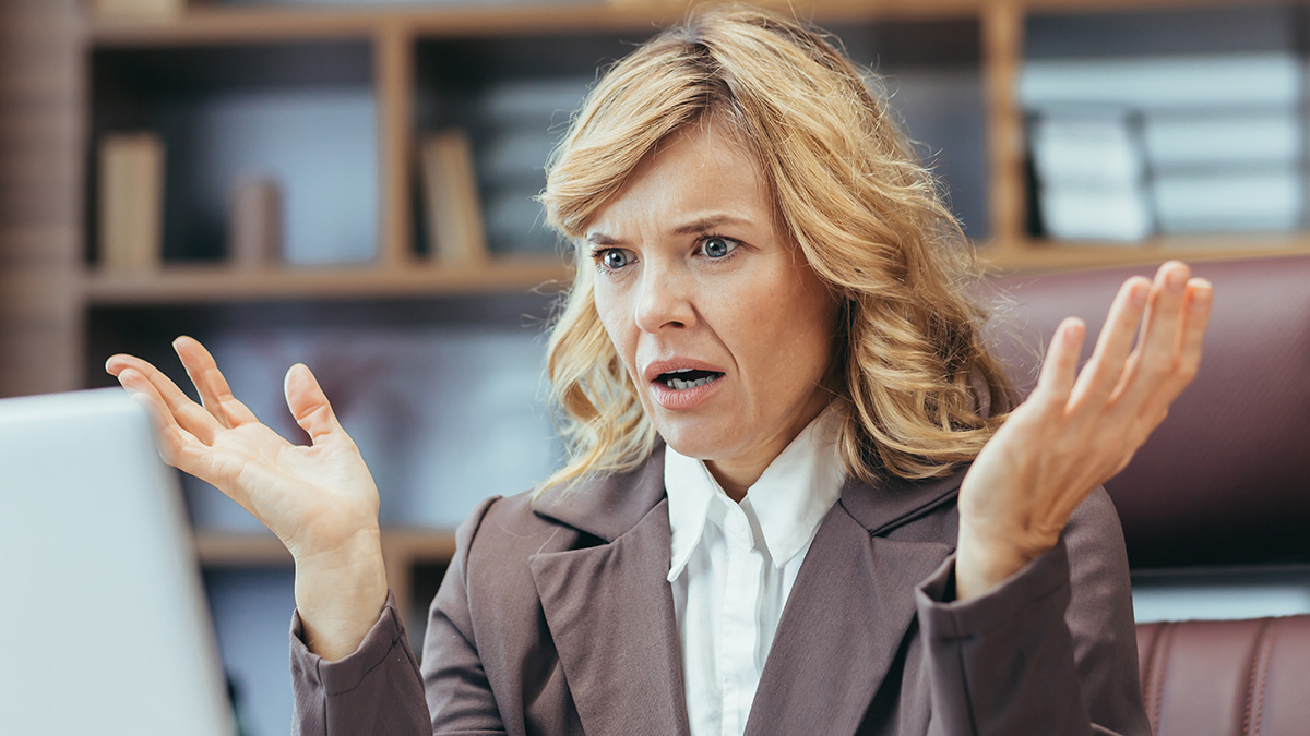 Office Karen looking shocked and frustrated at her desk while colleagues watch karma unfold in the workplace.