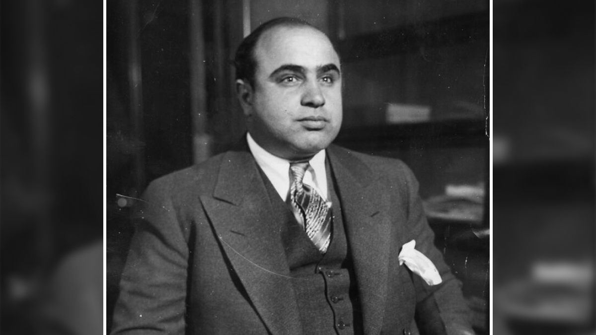 Black and white portrait of a notorious mob boss wearing a suit and tie, representing infamous mob bosses in history.