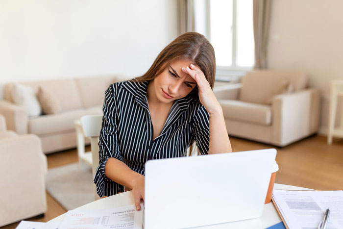 Woman stressed while working on laptop at home, reflecting tension over luxury vehicle and family plans conflict. Woman stressed while working on laptop at home, reflecting tension over luxury vehicle and family plans conflict.