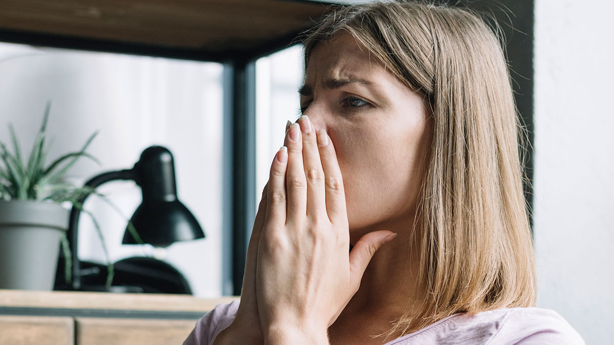 Young woman looking distressed, covering her mouth, illustrating work mistakes and recovery in a modern office setting.