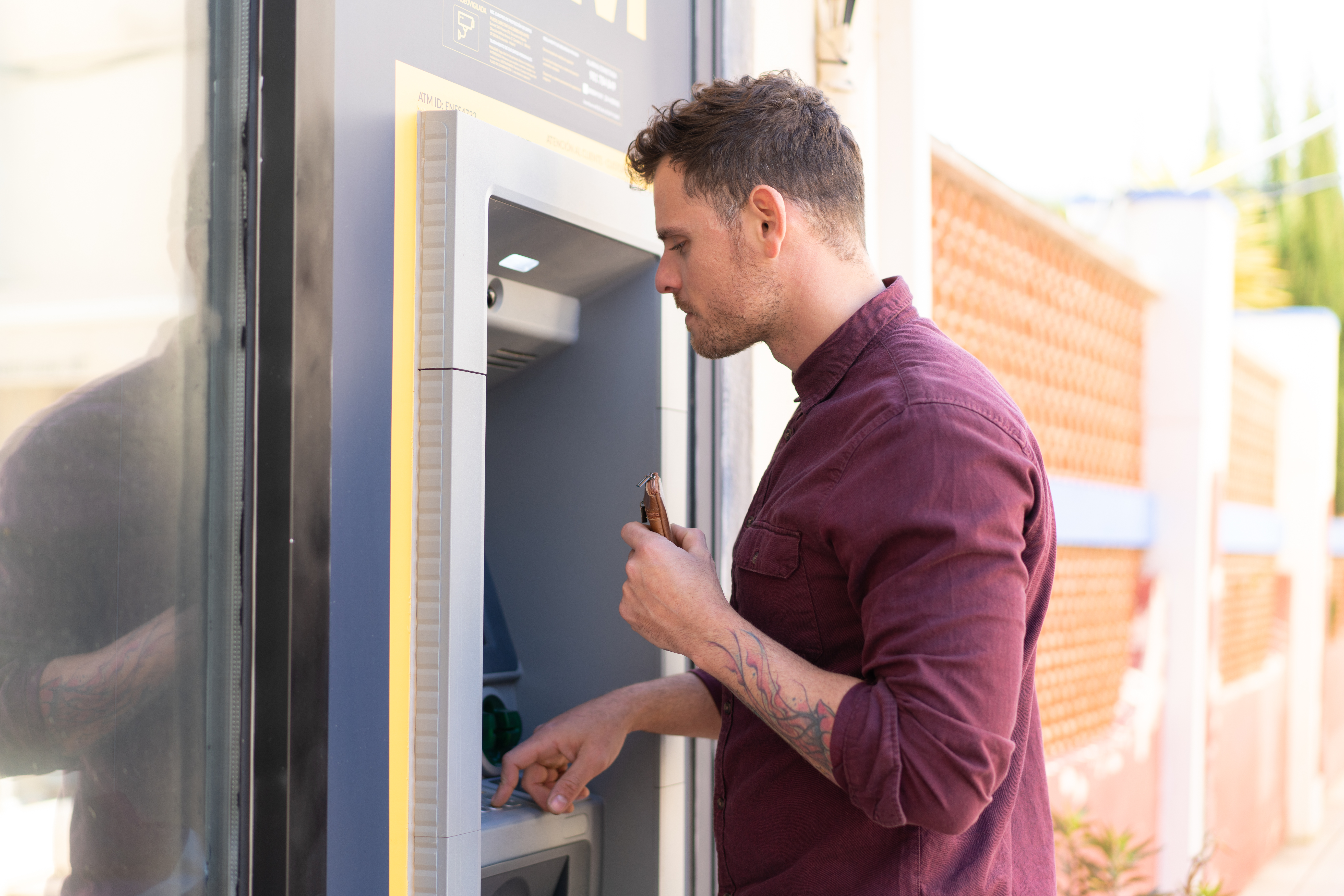 Man using ATM machine outdoors, illustrating bank funds access issue and impact on social media from Russian bots. Man using ATM machine outdoors, illustrating bank funds access issue and impact on social media from Russian bots.