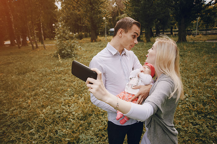Young siblings taking a selfie outdoors with a baby, capturing a moment of family and adoption connection. Young siblings taking a selfie outdoors with a baby, capturing a moment of family and adoption connection.