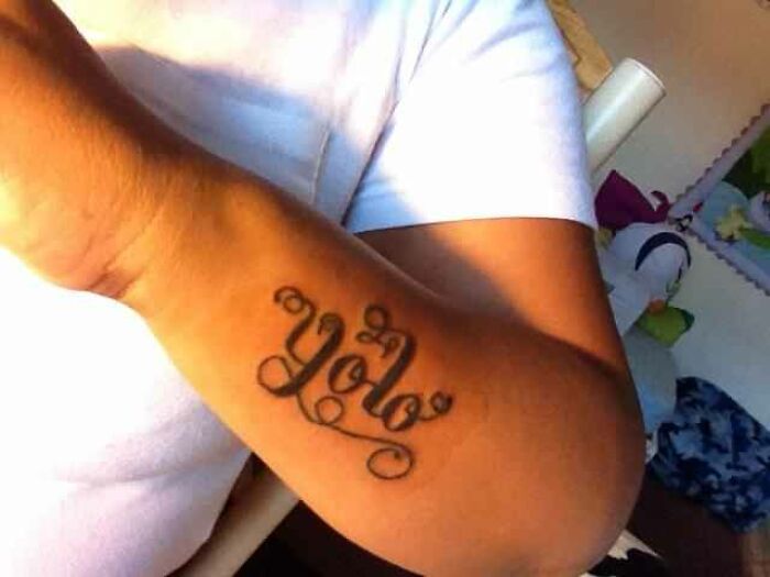 Forearm tattoo showing the word Yolo in cursive, illustrating one of the worst things clients wanted tattooed.