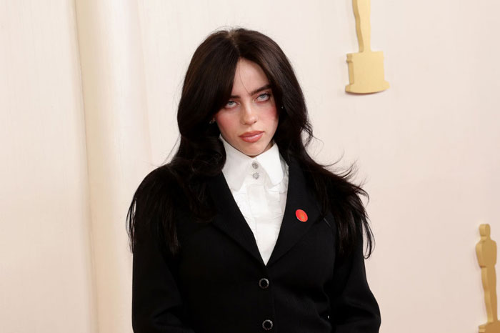 Billie Eilish wearing black suit and white shirt, looking serious amid fans outraged after Miami concert incident. Billie Eilish wearing black suit and white shirt, looking serious amid fans outraged after Miami concert incident.