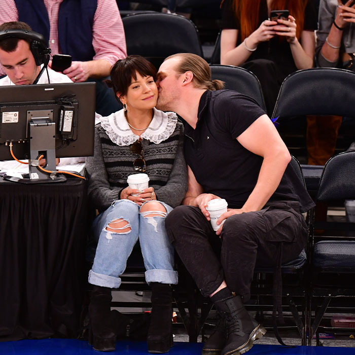 Lily Allen sitting courtside with a man whispering, both holding coffee cups, amid album and cheating controversy buzz. Lily Allen sitting courtside with a man whispering, both holding coffee cups, amid album and cheating controversy buzz.