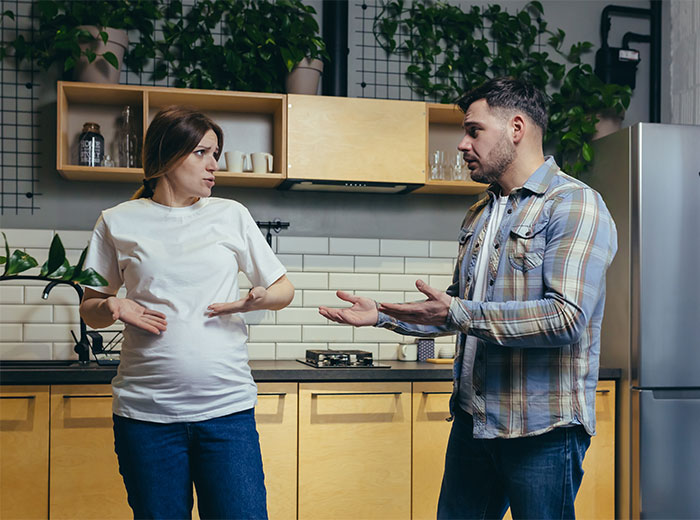 Pregnant woman and man in kitchen having a serious conversation about male best friend stepping into father role. Pregnant woman and man in kitchen having a serious conversation about male best friend stepping into father role.