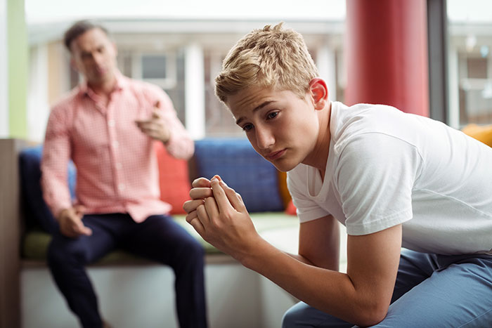 Teen looks upset while father talks in background, capturing a moment after a cake fail and strained family interaction. Teen looks upset while father talks in background, capturing a moment after a cake fail and strained family interaction.
