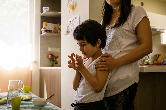 Teen and parent in kitchen after cake fail, showing mixed emotions and supportive embrace from adult. Teen and parent in kitchen after cake fail, showing mixed emotions and supportive embrace from adult.