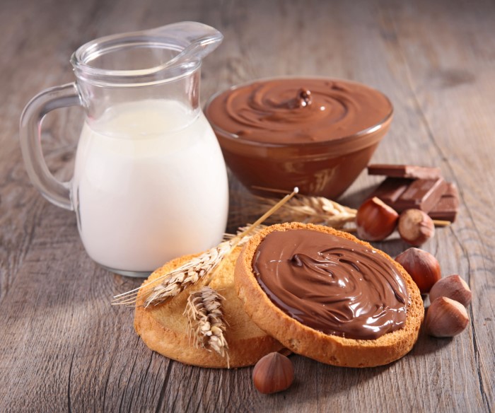 Milk, hazelnuts, and chocolate spread with wheat crackers on a wooden surface, illustrating food allergies and parents lied.