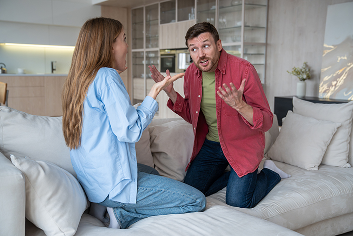 Woman and husband having a heated argument on couch about his Pokémon card collection in a modern living room setting. Woman and husband having a heated argument on couch about his Pokémon card collection in a modern living room setting.
