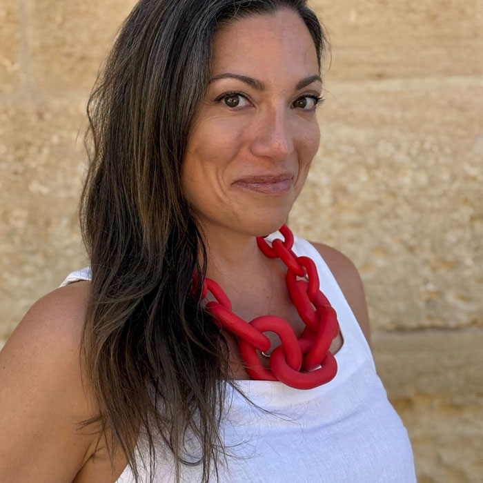 Woman with long dark hair and red necklace, recalling vacation regrets after using Meta glasses to record footage. Woman with long dark hair and red necklace, recalling vacation regrets after using Meta glasses to record footage.