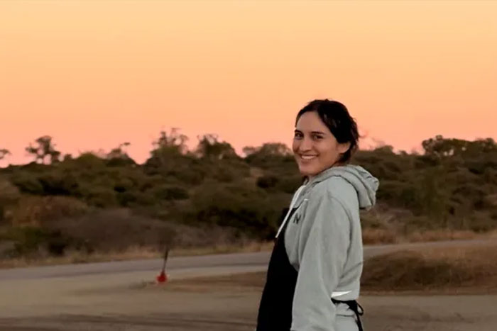 Woman standing outdoors at sunset, smiling, related to story of bird injury and insurance coverage denial. Woman standing outdoors at sunset, smiling, related to story of bird injury and insurance coverage denial.