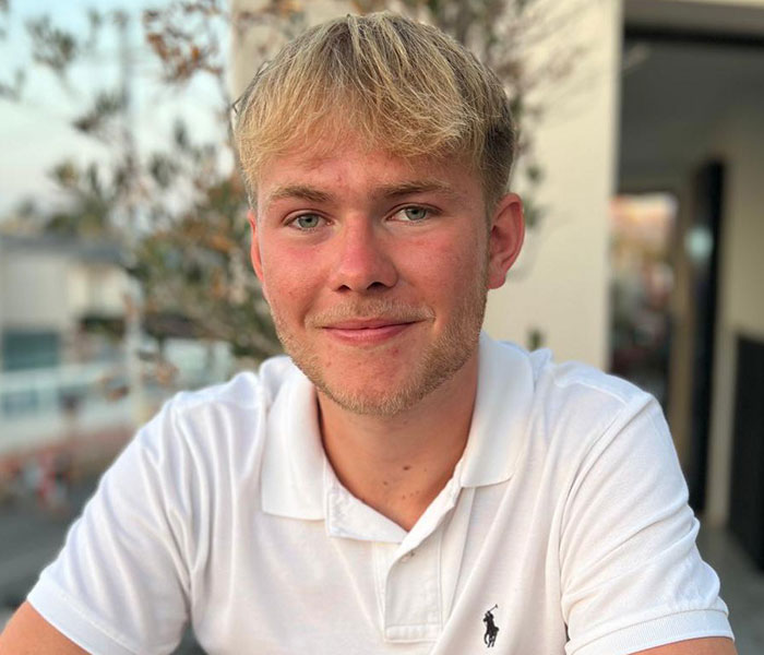 Young man with blonde hair wearing a white polo shirt, smiling outdoors after deciding to amputate his leg post rock concert. Young man with blonde hair wearing a white polo shirt, smiling outdoors after deciding to amputate his leg post rock concert.