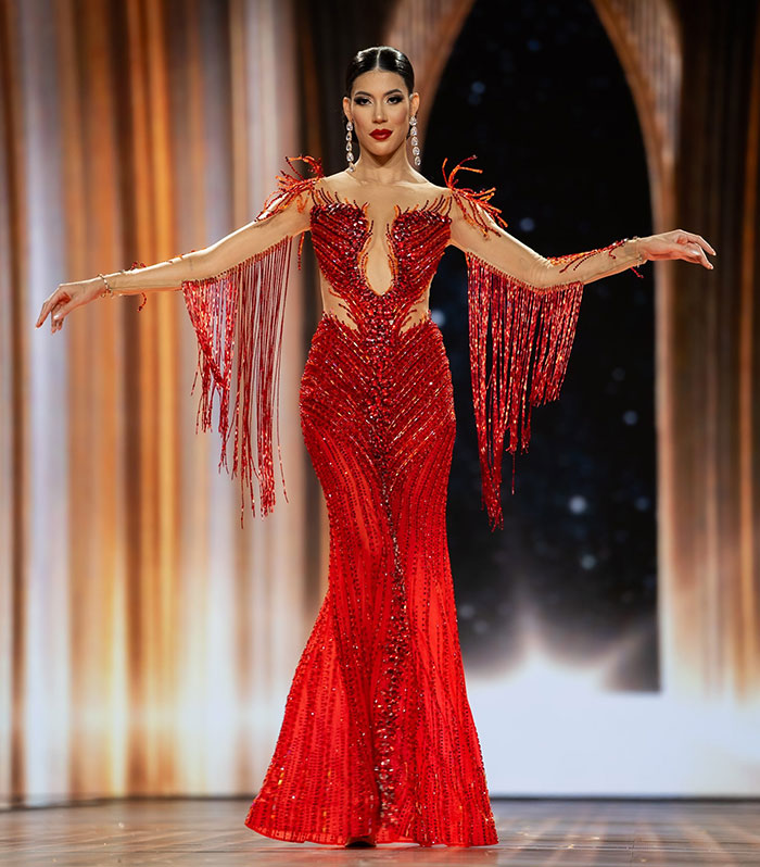 Miss Panama wearing an elaborate red gown with fringe details, posing onstage during a beauty pageant event. Miss Panama wearing an elaborate red gown with fringe details, posing onstage during a beauty pageant event.