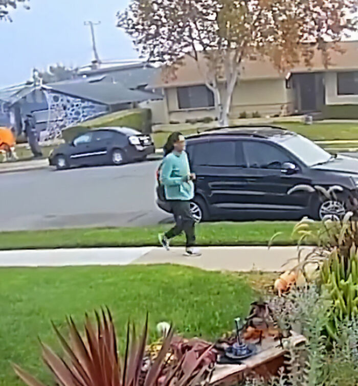 Woman walking near Halloween witches decoration in neighborhood during bizarre viral incident caught on camera