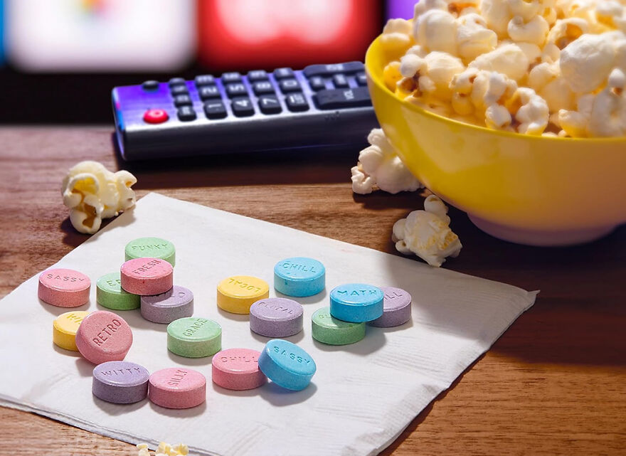 Colorful candy hearts on a napkin beside a bowl of popcorn and a TV remote showing popular Halloween candy in 2025.