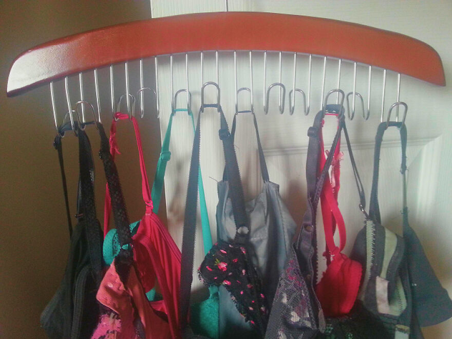 Bra straps hanging on a wooden multi-hook organizer showcasing creative organization hacks for home storage solutions.