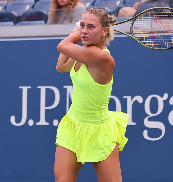 Female tennis player in bright yellow outfit preparing to hit a backhand during a professional match scene. Female tennis player in bright yellow outfit preparing to hit a backhand during a professional match scene.
