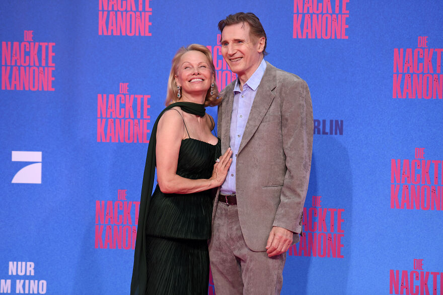 Pamela Anderson and Liam Neeson posing on red carpet event with backdrop, related to Pamela Anderson's net worth and decades of reinvention. Pamela Anderson and Liam Neeson posing on red carpet event with backdrop, related to Pamela Anderson's net worth and decades of reinvention.