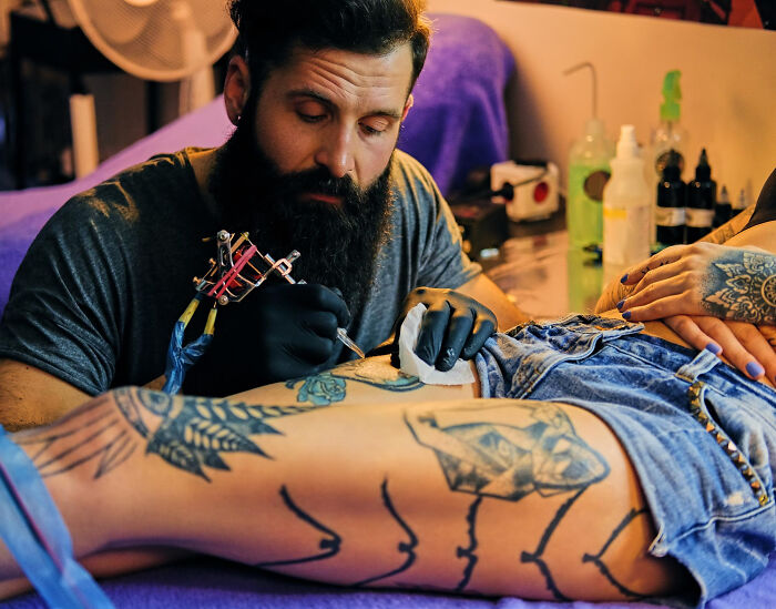 Tattoo artist carefully working on client’s thigh, illustrating moments when tattoo artists drew the line with certain requests.