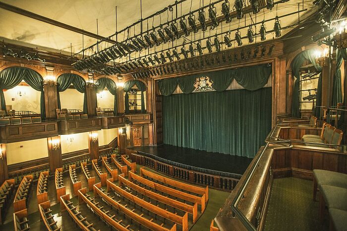 Historic theater interior with wooden seating and stage lighting, a spooky destination perfect for Halloween visits.