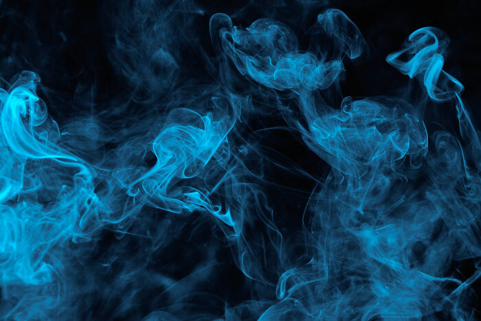 Blue smoke swirling against a black background, symbolizing shocking things popular kids did in school turning them into outcasts.