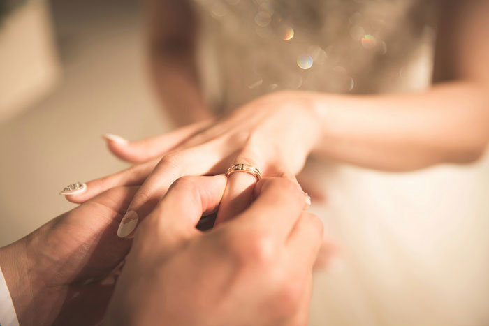 Close-up of a groom placing a wedding ring on a bride&rsquo;s finger during a wedding ceremony on American soil.