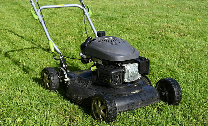 Old black lawn mower on green grass, symbolizing stories about the worst crimes in hometowns shared by people.
