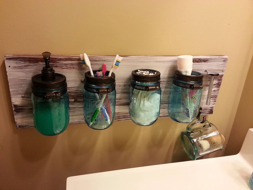 Wall-mounted blue mason jars used as organization hacks for bathroom essentials in a home setting.