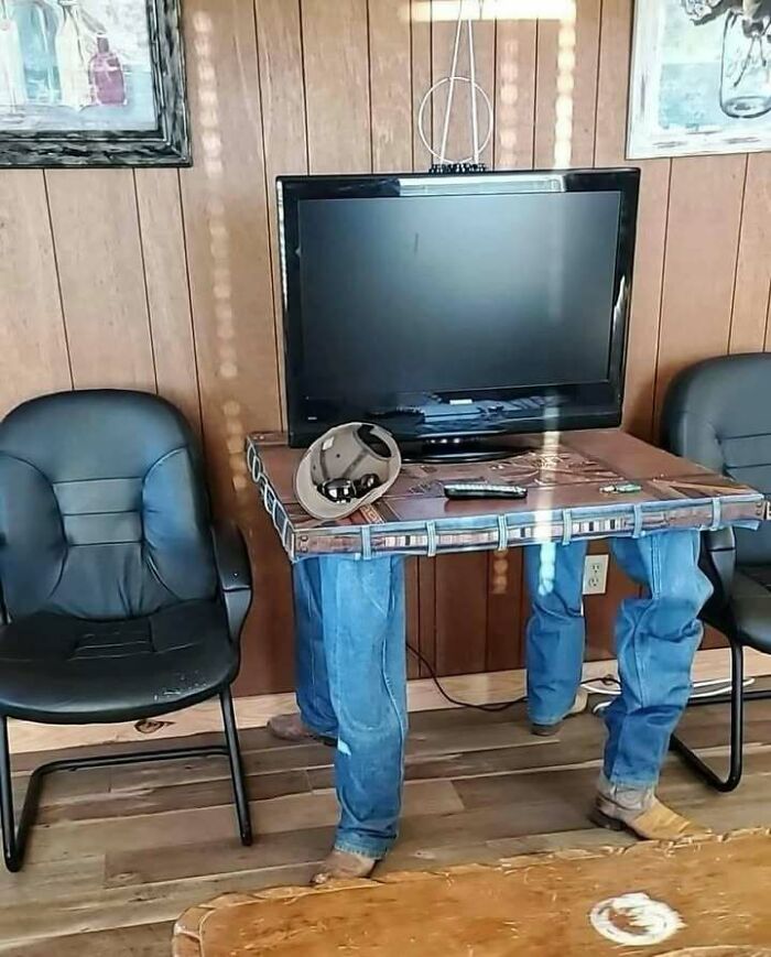 Table with realistic legs wearing jeans and boots holding a TV, one of the confusing images where things only get weirder.