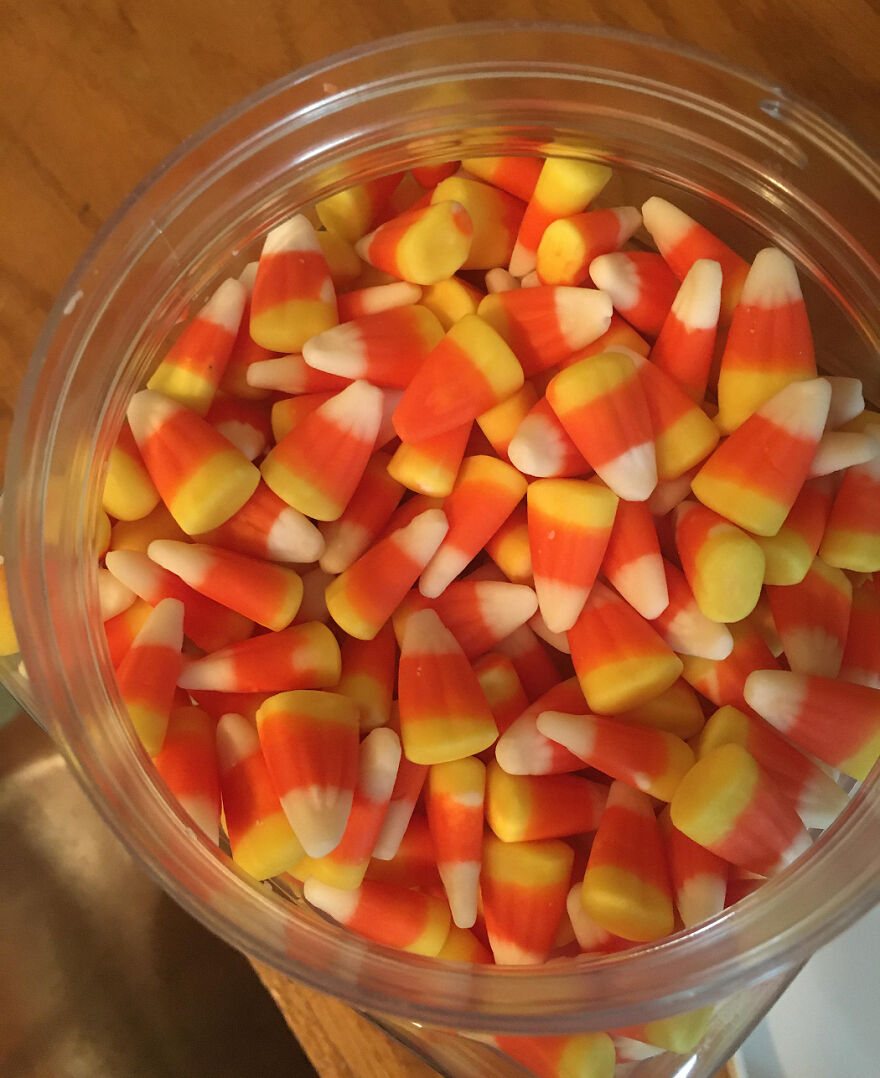 Close-up of classic candy corn in a clear container, a popular Halloween candy for 2025 celebrations and treats.