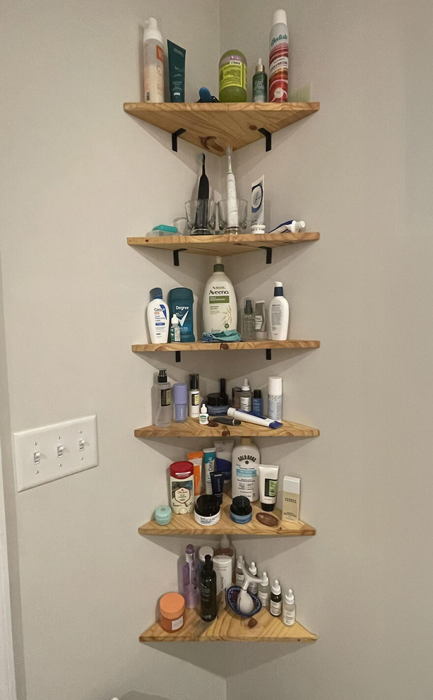 Corner wooden shelves neatly organizing various skincare and personal care products in a home bathroom setting