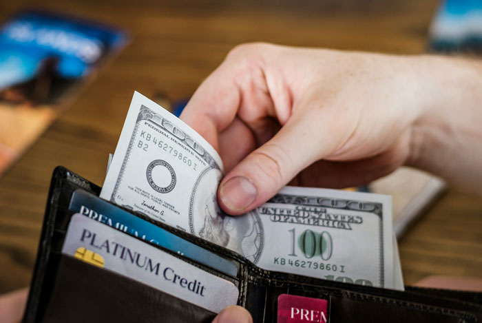 Hand holding cash and putting a hundred dollar bill in a wallet, waiter assumed 40 change was tip situation concept. Hand holding cash and putting a hundred dollar bill in a wallet, waiter assumed 40 change was tip situation concept.