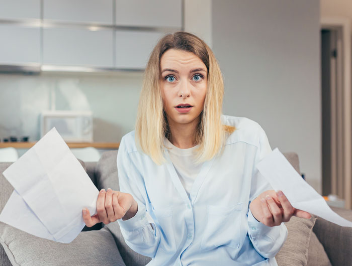 Woman in a living room looking confused and holding papers, depicting drama from a fake adoption family plan. Woman in a living room looking confused and holding papers, depicting drama from a fake adoption family plan.