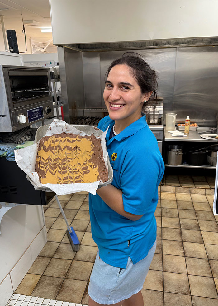 Woman smiling in kitchen holding tray with patterned dessert, related to insurance company denied coverage over bird incident. Woman smiling in kitchen holding tray with patterned dessert, related to insurance company denied coverage over bird incident.