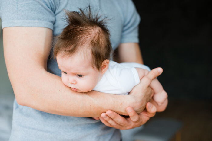Man holding baby in his arms, highlighting relationships impacted by unfair gender roles and dynamics.